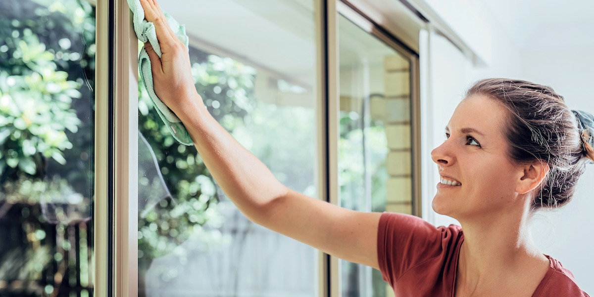 Young woman cleaning window - House Cleaner